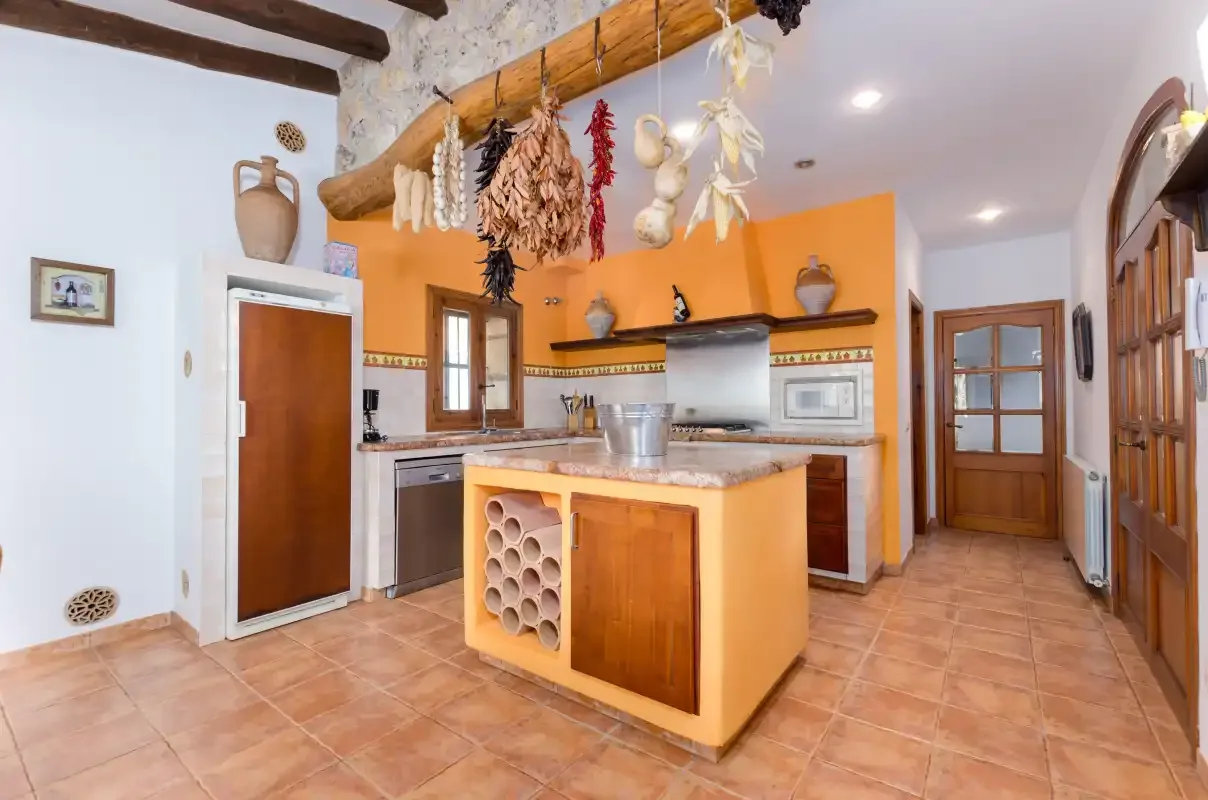 A kitchen with an island, wooden cabinetry, and exposed ceiling beams.