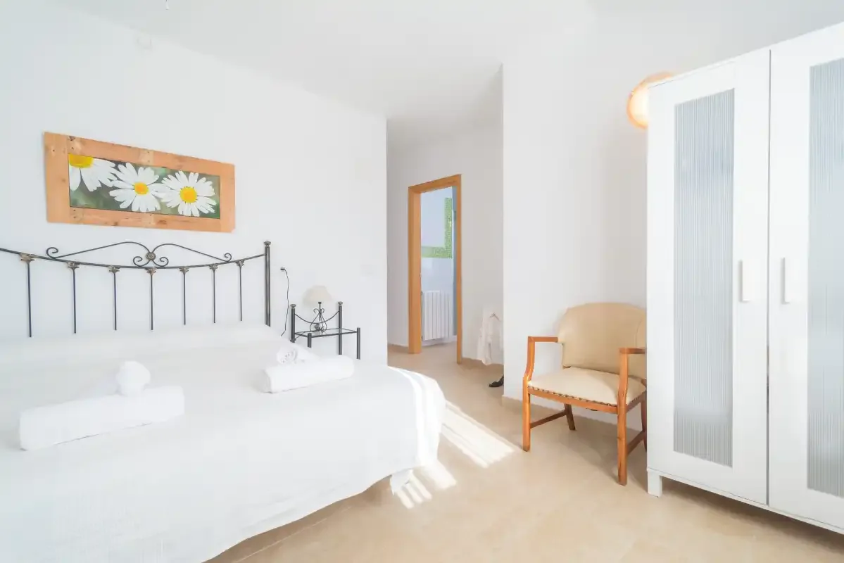 A bright bedroom with a large bed and a wooden chair.