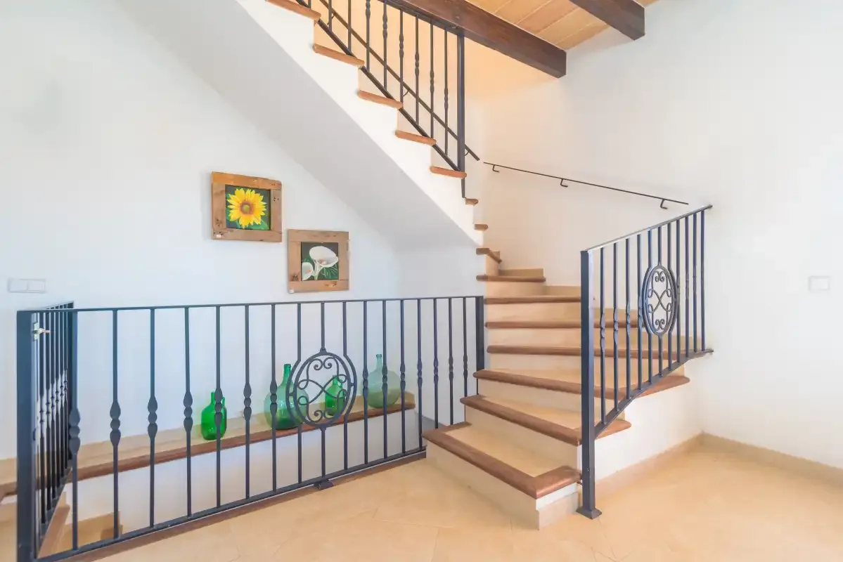 An indoor staircase with wooden steps and dark metal railings.