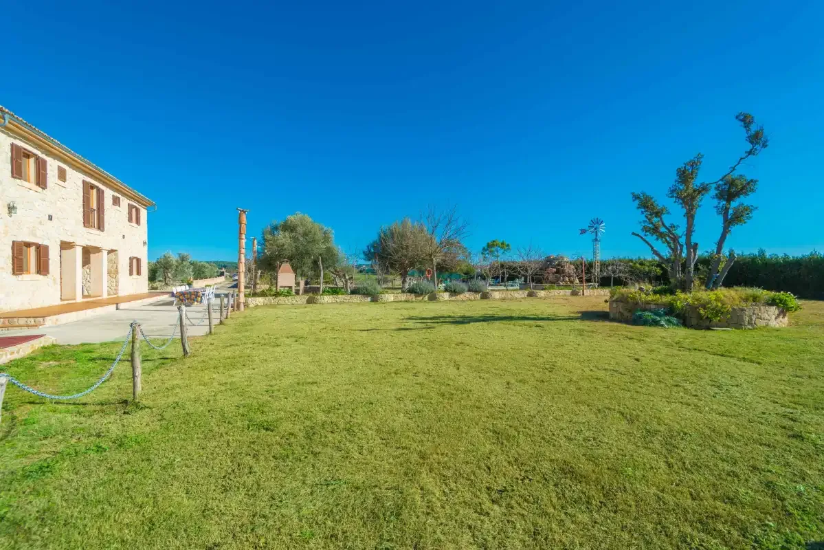 A grassy garden stretches beside a stone building under a clear blue sky.
