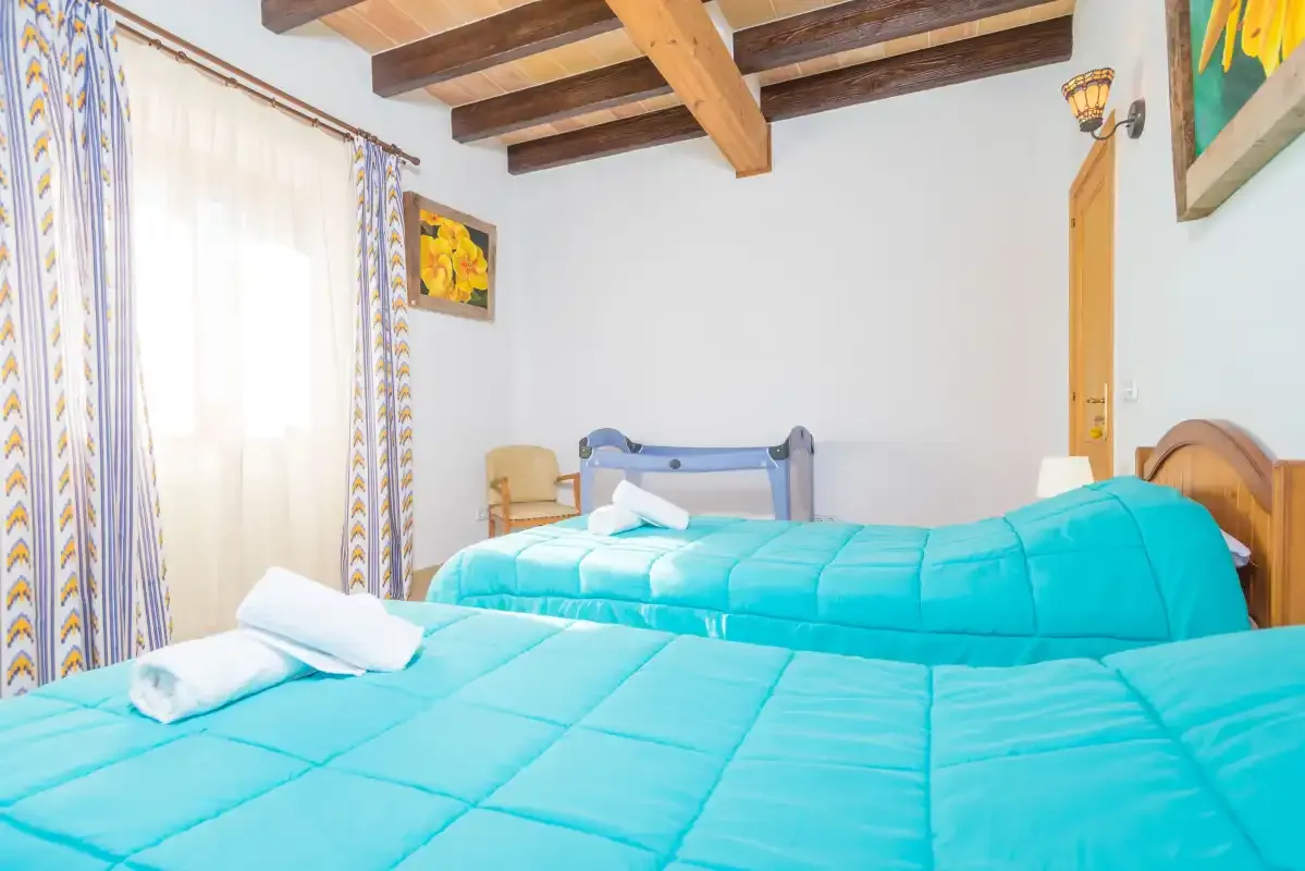 A bedroom with two beds covered in bright turquoise bedding.