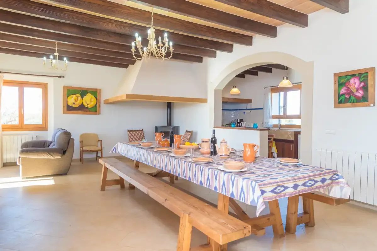 A dining area with a long table set beside an open kitchen.