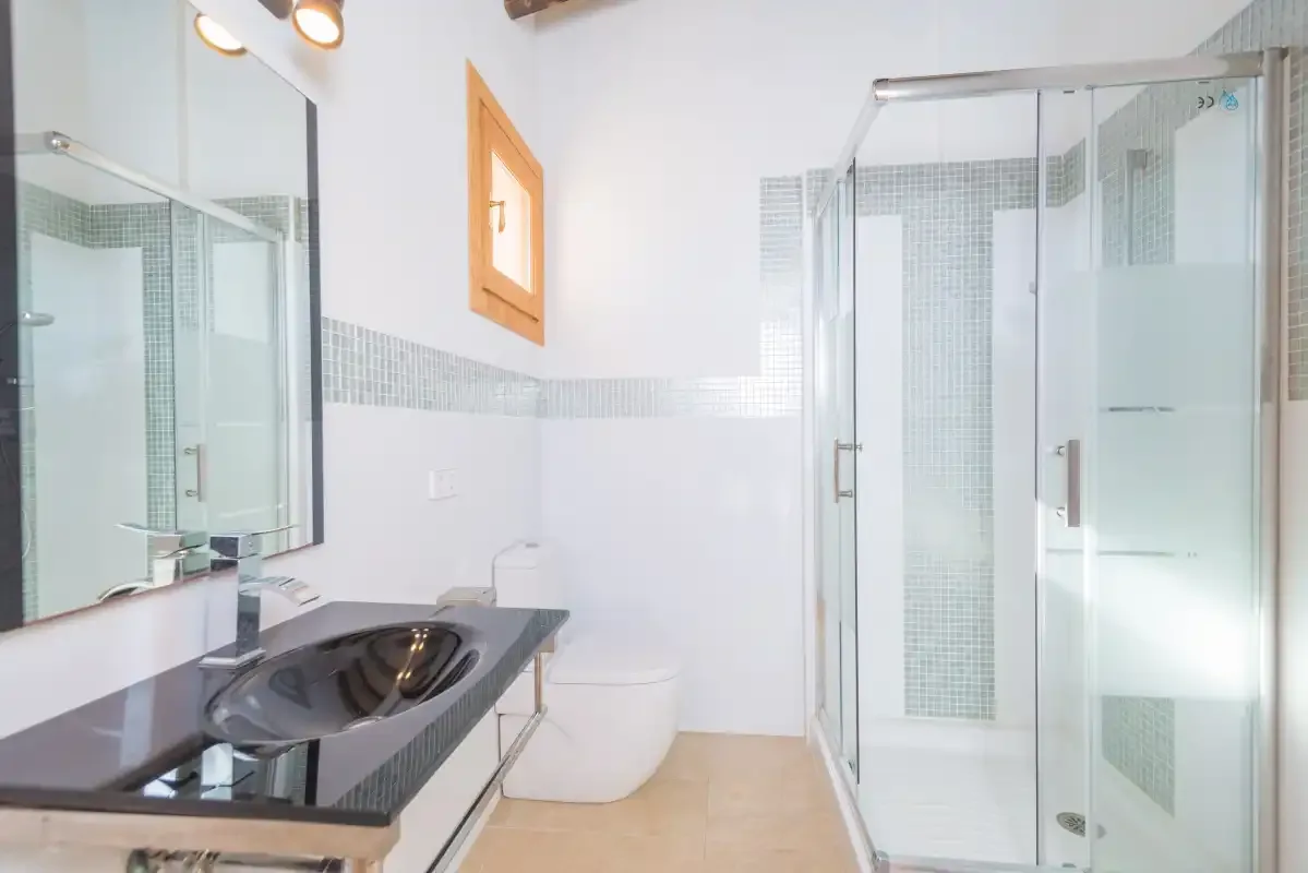 A bright bathroom with a vanity, toilet, and glass shower.