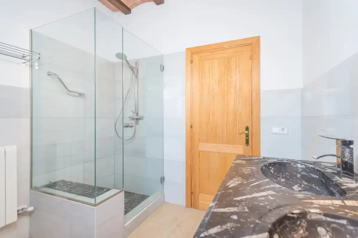 A bathroom with a glass shower and a sink.