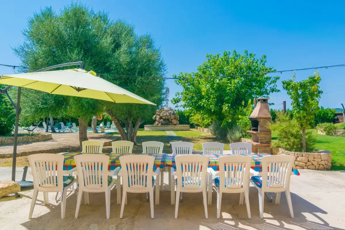 Outdoor dining area with white seating beneath a large patio umbrella.