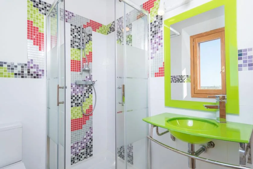 A bright bathroom with a glass shower and a lime-green sink counter.