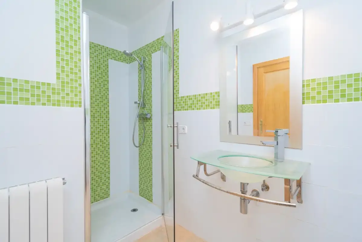 A bright bathroom with a glass shower and a sink beneath a mirror.