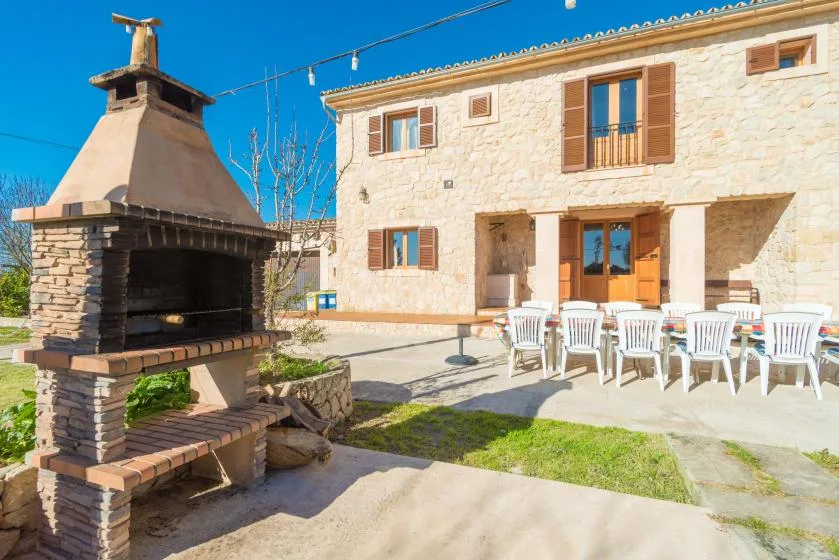 A stone house patio with outdoor seating and a large masonry barbecue.