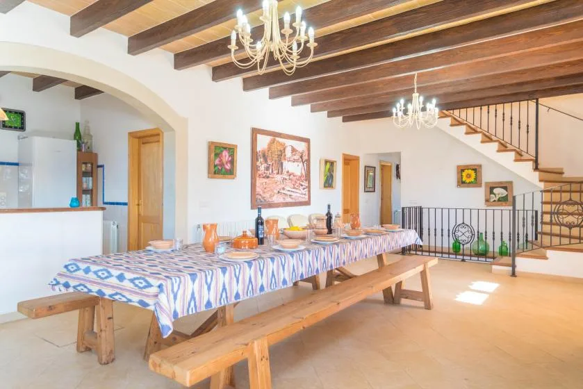 A dining area with a long table, benches, and exposed ceiling beams.