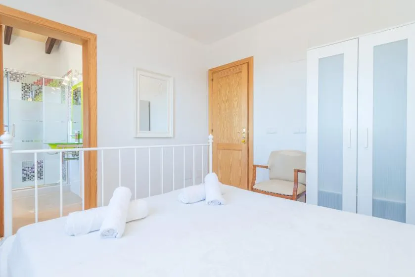 A bright bedroom with a neatly made bed and white wardrobe.