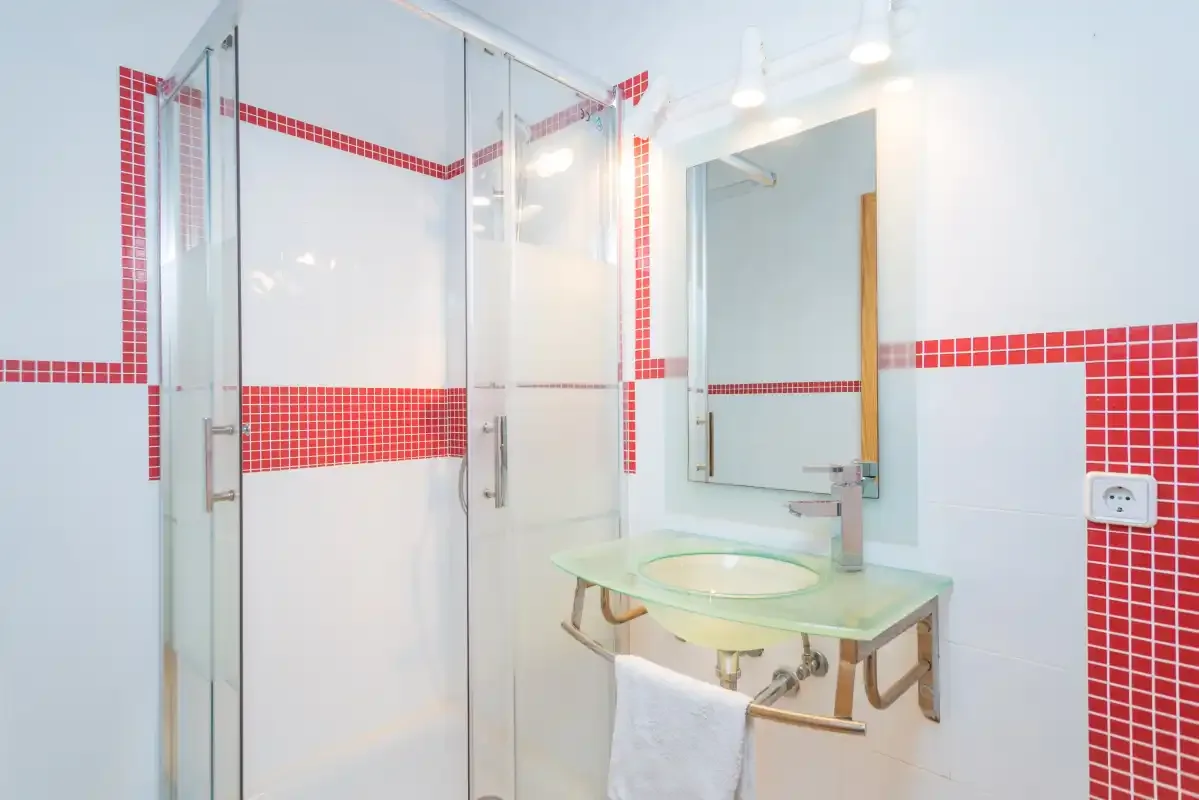 A bright bathroom has a glass shower and a sink with a mirror.