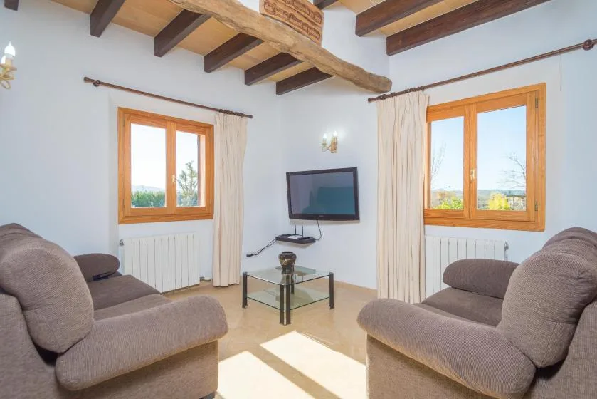 A bright living room with seating, a television, and windows.