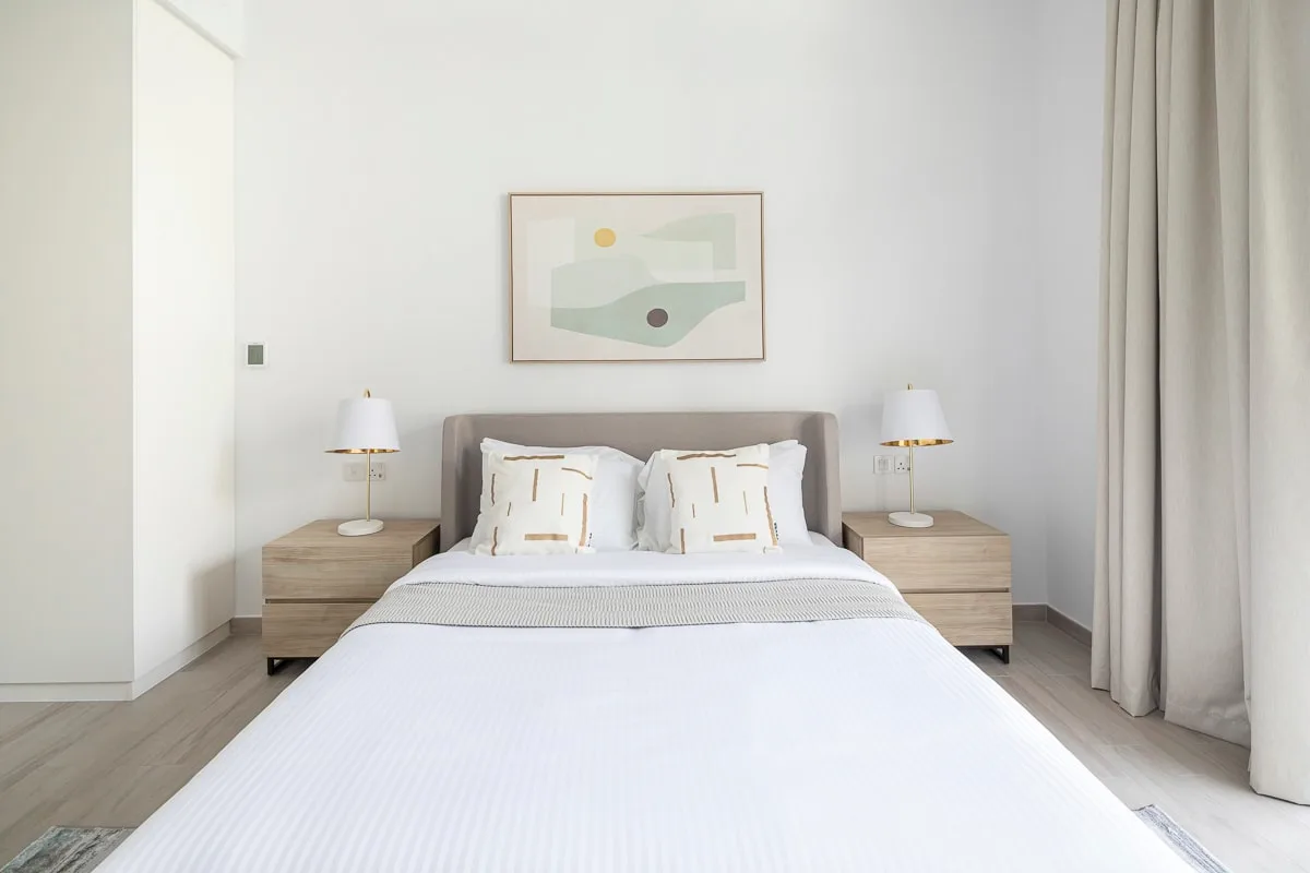 Un dormitorio luminoso con una cama bien hecha y mesitas de noche a juego.