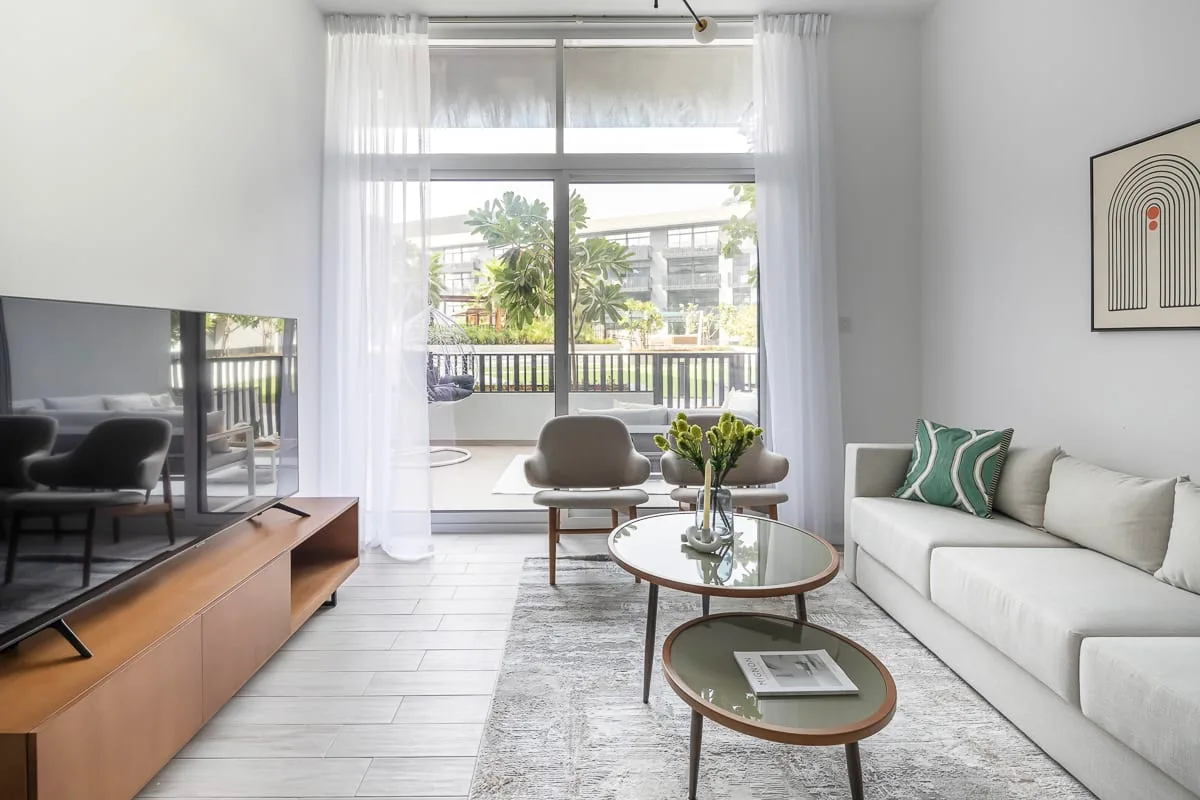 Una sala luminosa con asientos, mesas de vidrio y una ventana amplia con vista al balcón.