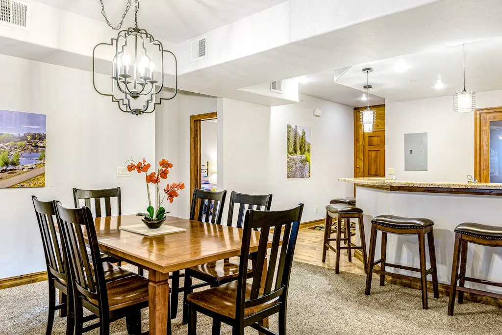 A dining area with a wooden table and stools at a kitchen counter.