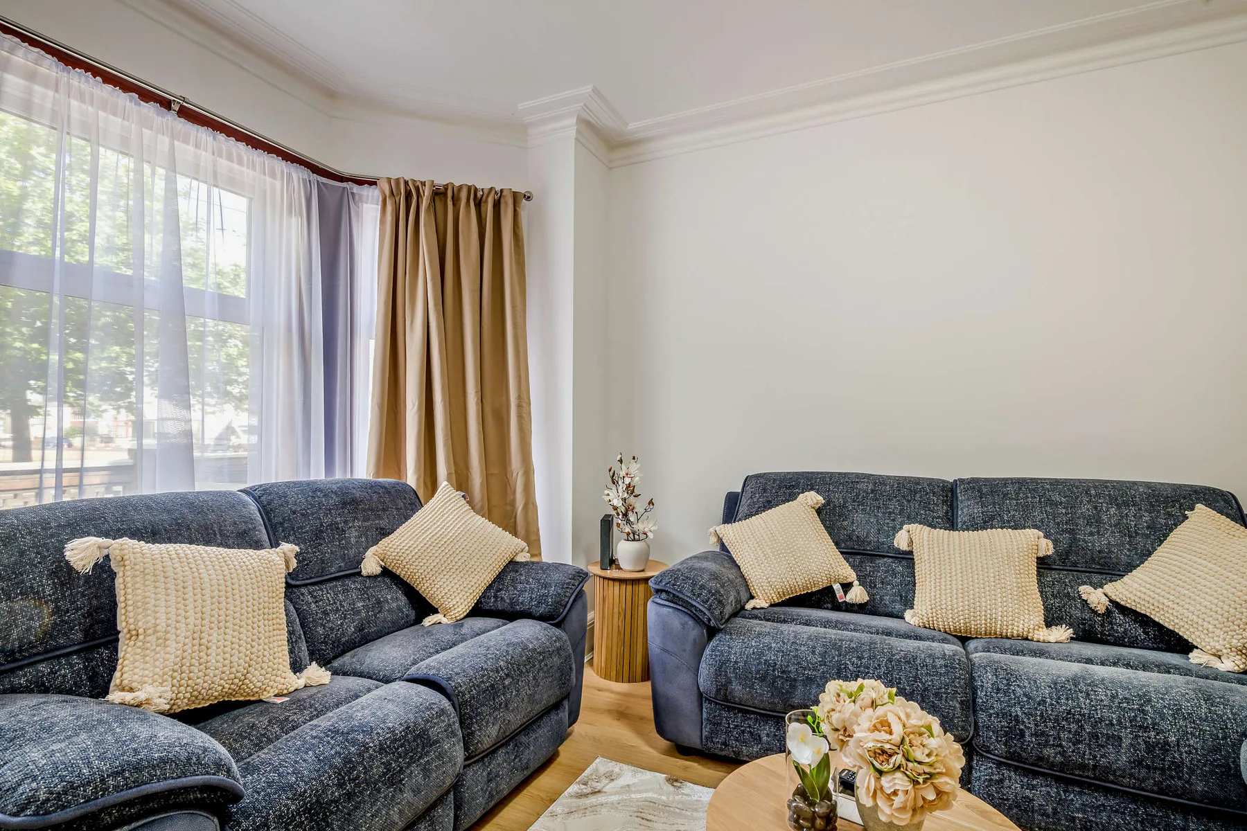 Una sala de estar con asientos azules y una gran ventana con cortinas.