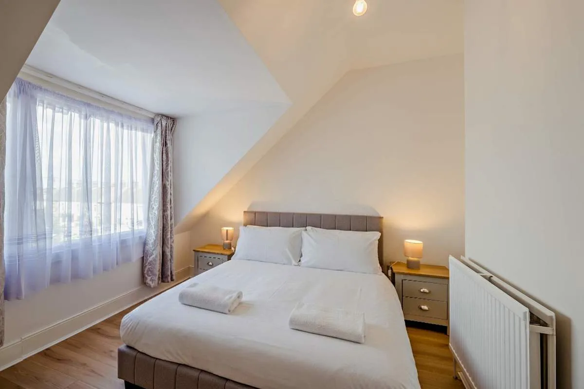 Un dormitorio luminoso con una cama doble bajo un techo inclinado.