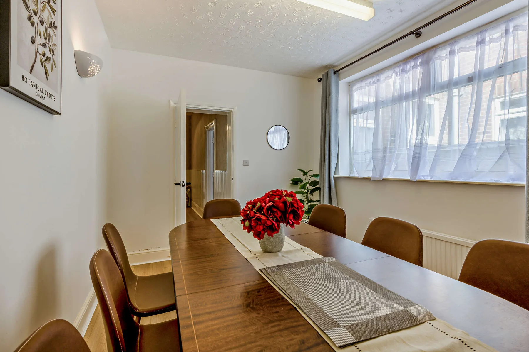 Un comedor con una mesa larga, sillas y una gran ventana con cortinas.