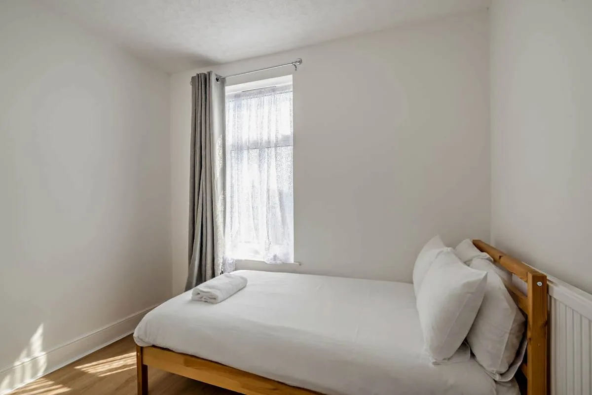 Un dormitorio con una cama junto a una ventana con cortinas.