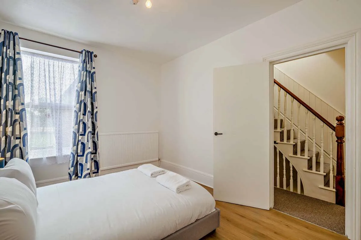 Dormitorio con una cama junto a una ventana y una puerta abierta.