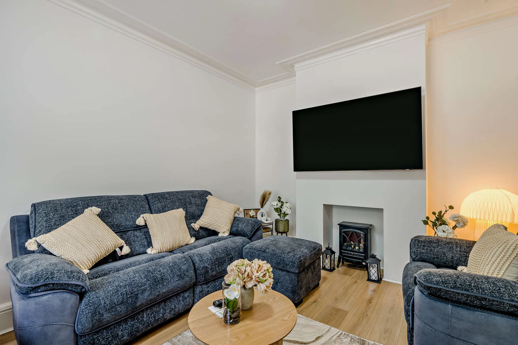 Una sala de estar con asientos azules, una chimenea y un televisor.