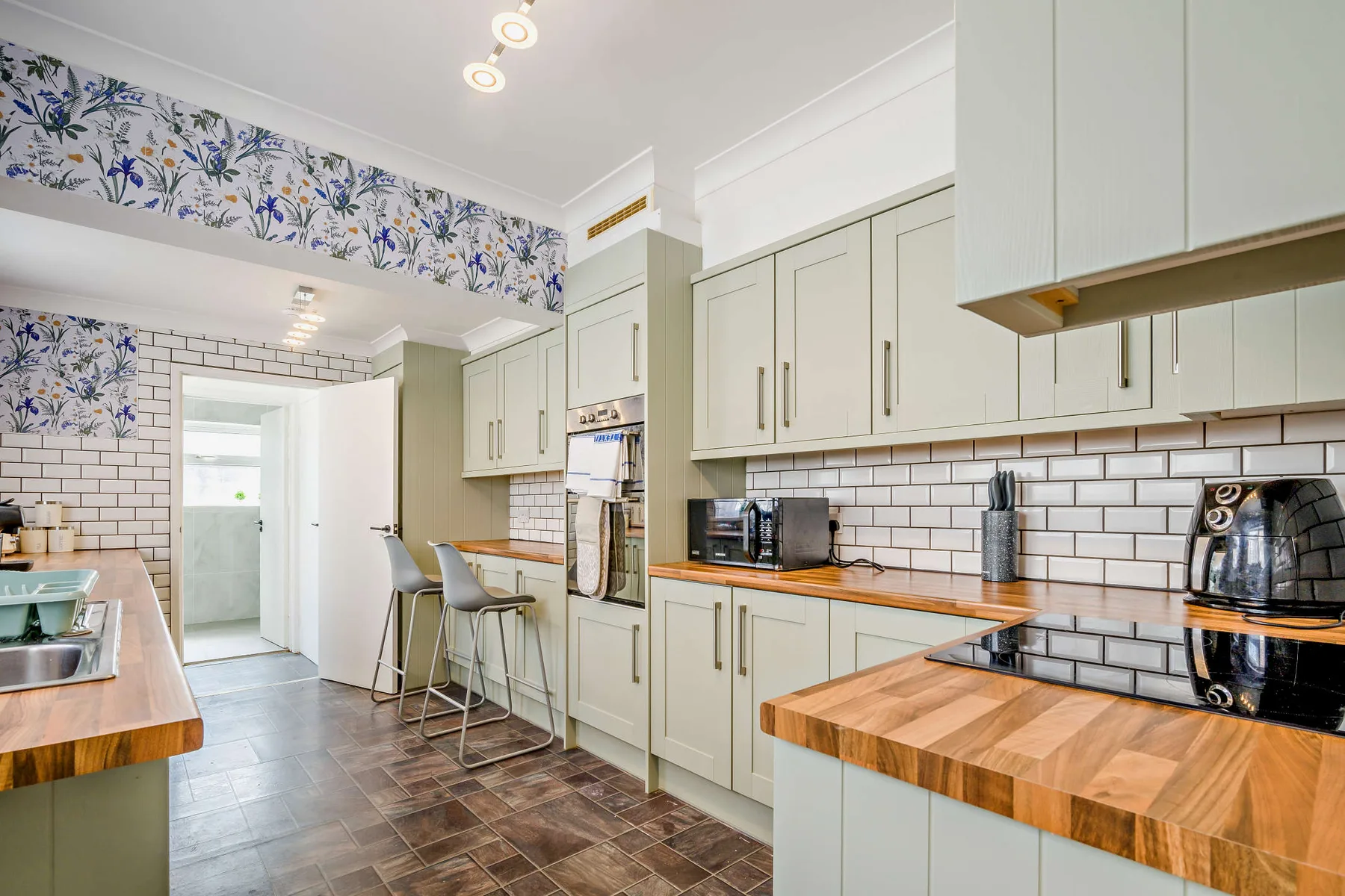 Una cocina luminosa con gabinetes claros, paredes revestidas de azulejos y encimeras de madera.