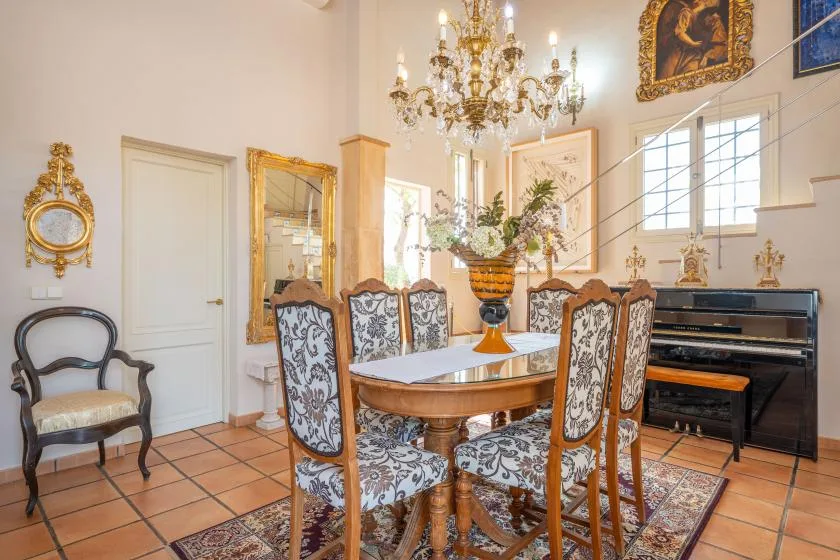 Un comedor formal con una mesa ornamentada, sillas estampadas y una lámpara de araña.