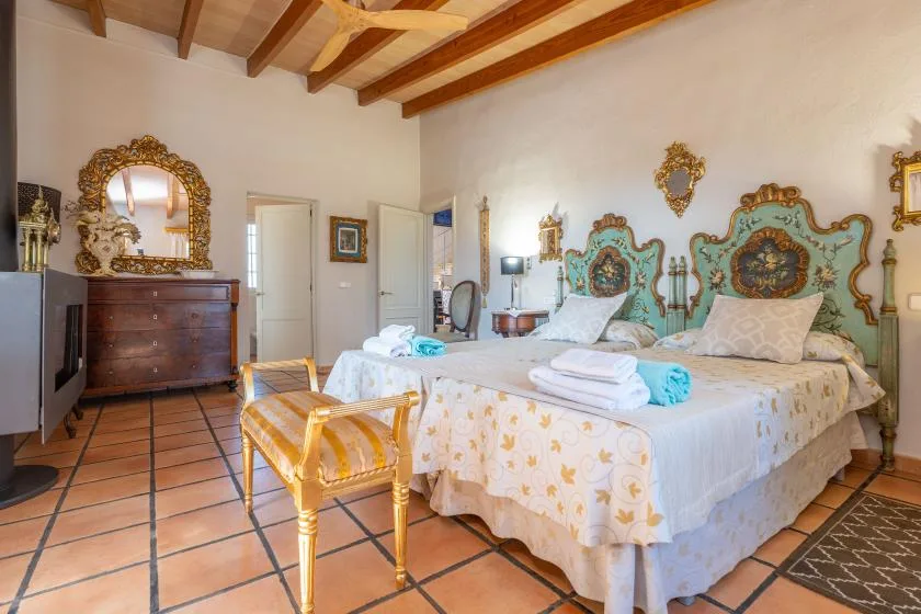 Un dormitorio con dos camas, cabeceros ornamentados y vigas de madera a la vista.