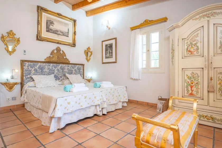 Un dormitorio con cama doble, cuadros enmarcados y un armario decorado.
