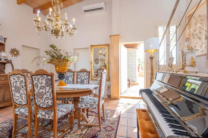 Un comedor luminoso con asientos estampados y un piano junto a la mesa.