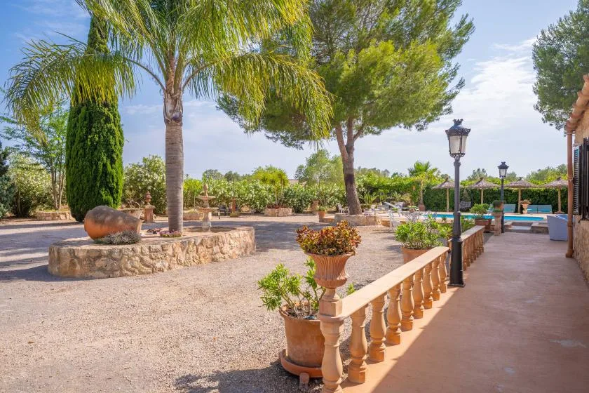 Un patio ajardinado con palmeras, jardineras de piedra y un sendero pavimentado.