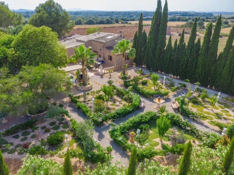 Vista aérea de un edificio de piedra rodeado de jardines cuidados y árboles altos.
