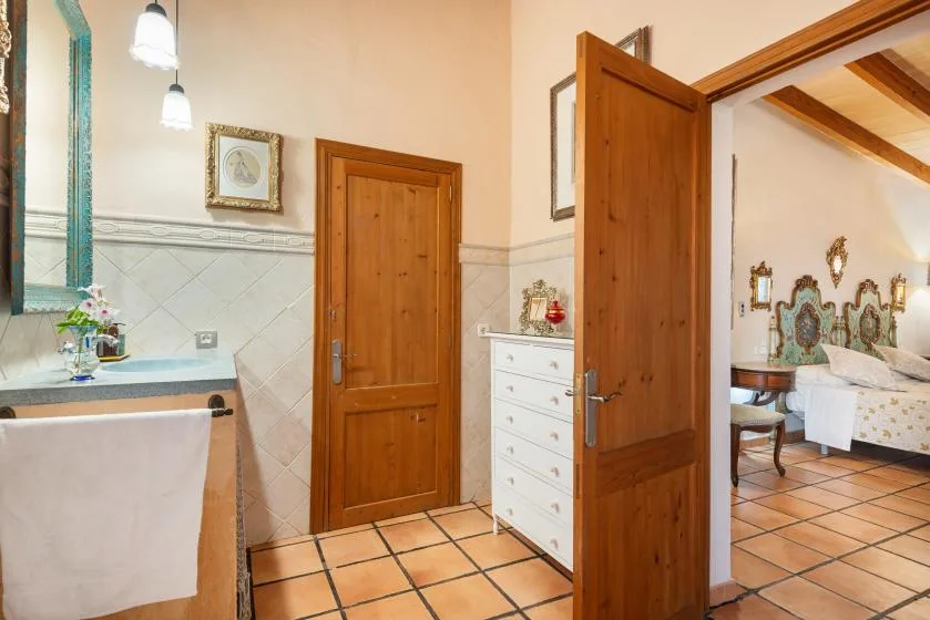 Un baño con suelo de baldosas se abre por una puerta de madera a una estancia con asientos.