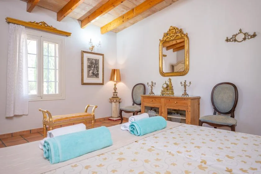 Un dormitorio con una cama de madera, una mesita y un espejo ornamentado sobre una cómoda.