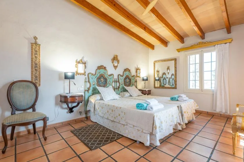 Un dormitorio con una cama grande, un cabecero decorativo y vigas de madera a la vista.