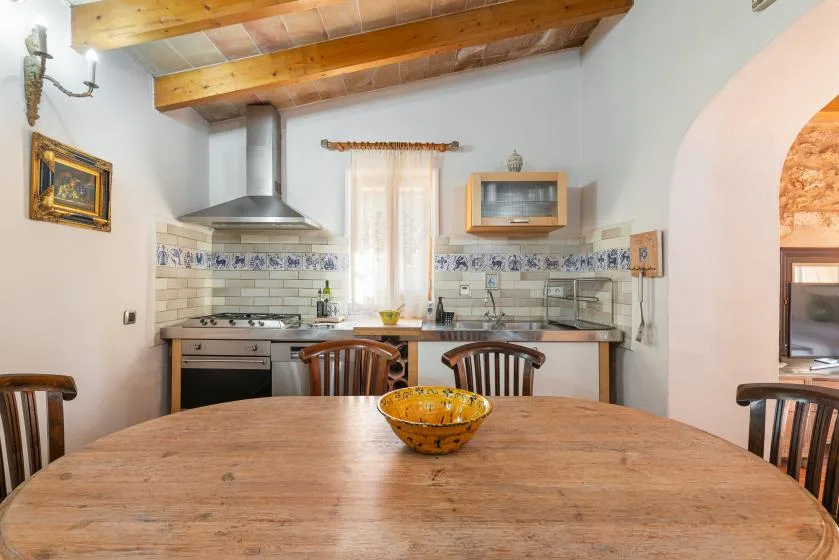 Cocina y comedor con una mesa de madera bajo vigas de techo expuestas.