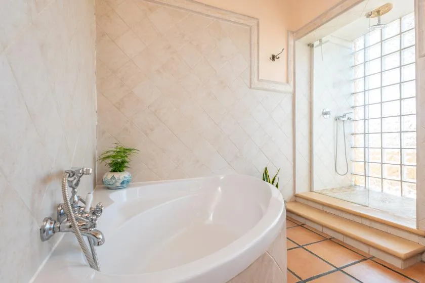 Un baño con una bañera grande junto a una zona de ducha con bloques de vidrio.