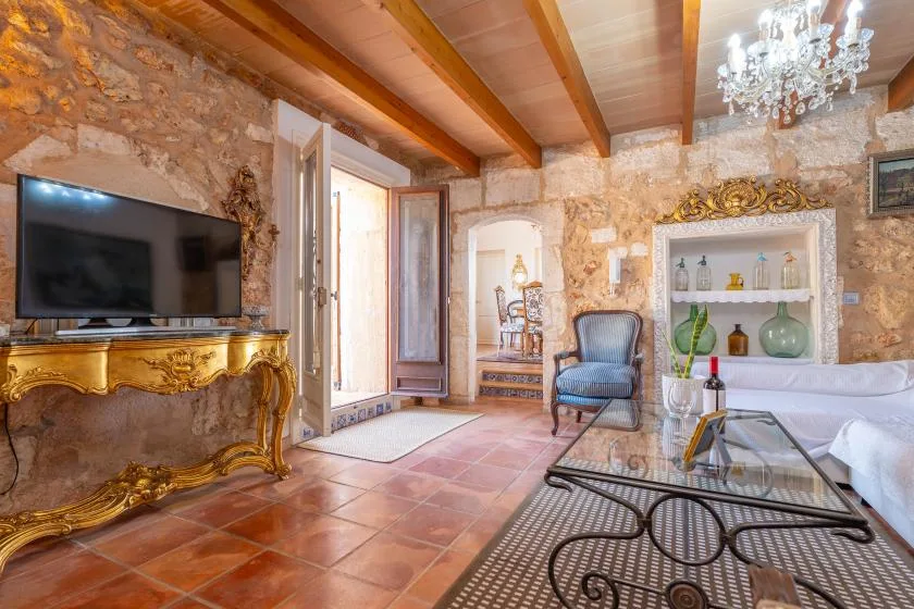 Una sala de estar con paredes de piedra, televisión, asientos y una mesa de centro de vidrio.