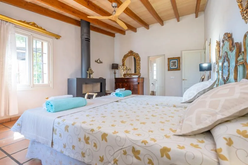 Un dormitorio con una cama grande, vigas de madera a la vista y una ventana.
