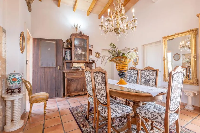 Un comedor formal con una mesa larga, asientos estampados y una lámpara de araña.