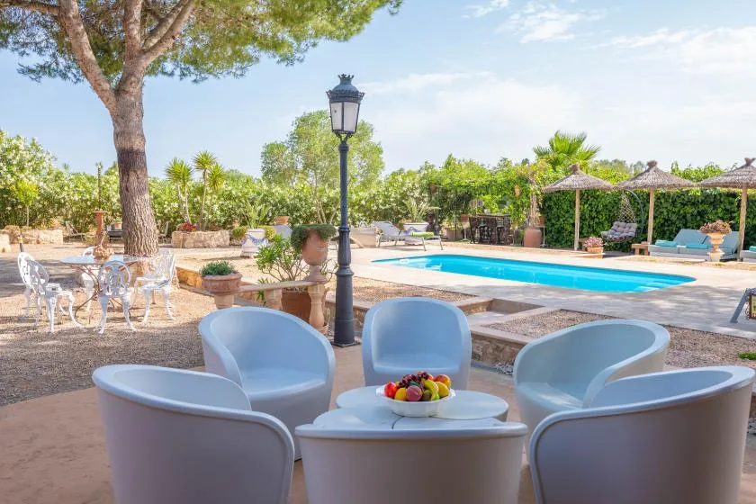Una zona de piscina al aire libre con asientos, una mesa y vegetación.