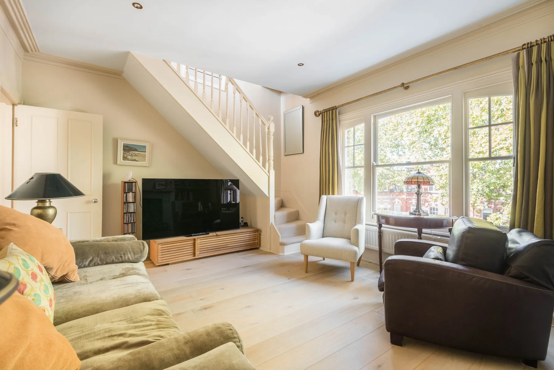 A bright living room with seating, a television, and large windows.