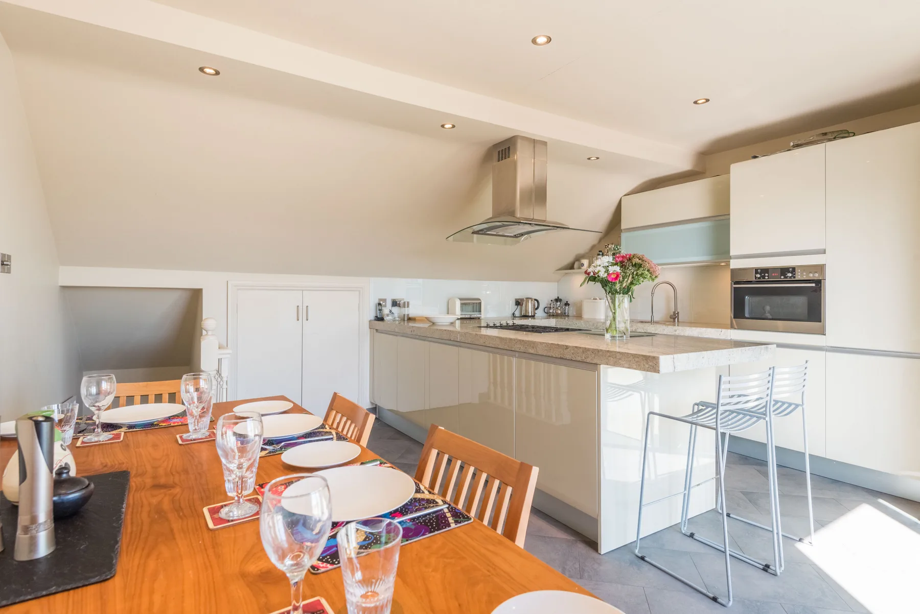 A modern kitchen and dining area with a wooden table and countertop seating.