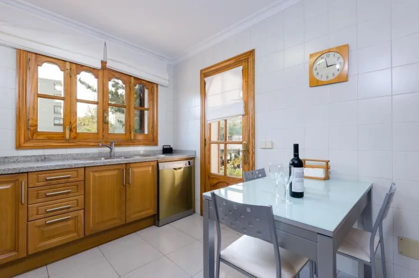 A bright kitchen with wooden cabinets, a dining table, and chairs.