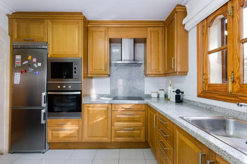 A kitchen with wooden cabinets, built-in appliances, and a countertop sink.