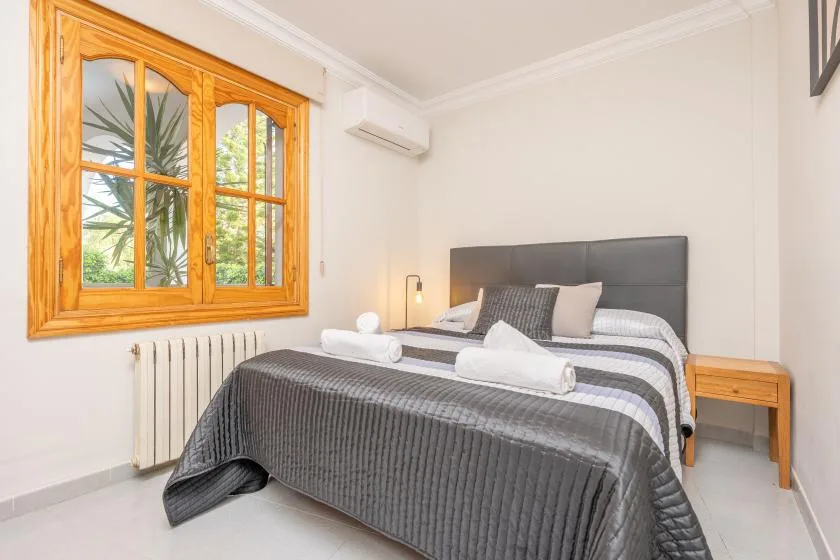 A bedroom with a double bed, striped bedding, and a wooden-framed window.