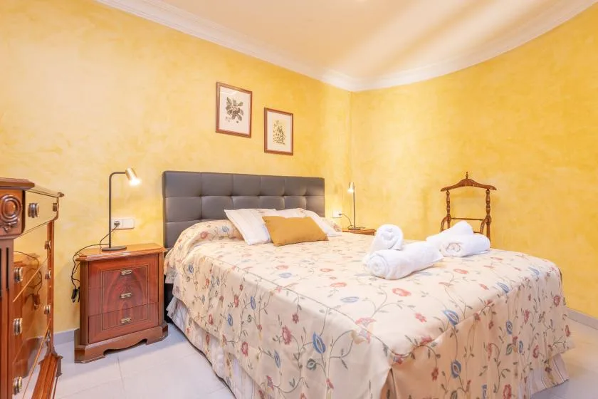 A bedroom with a bed, bedside table, and folded towels on the bed.