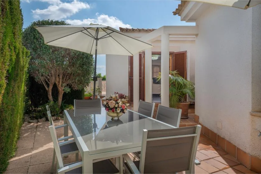 An outdoor dining area with a glass table beneath a large umbrella.