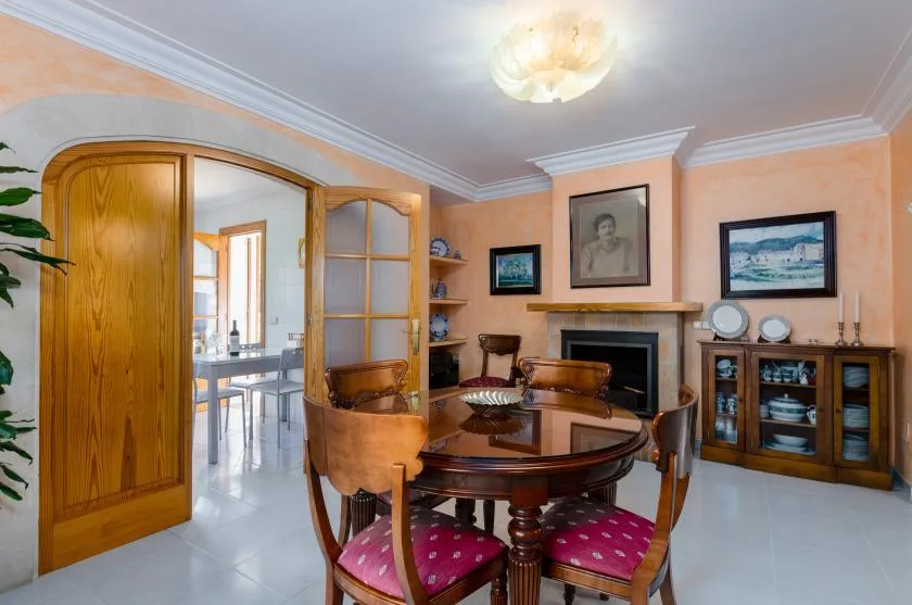 A formal dining room with a round wooden table and framed artwork.