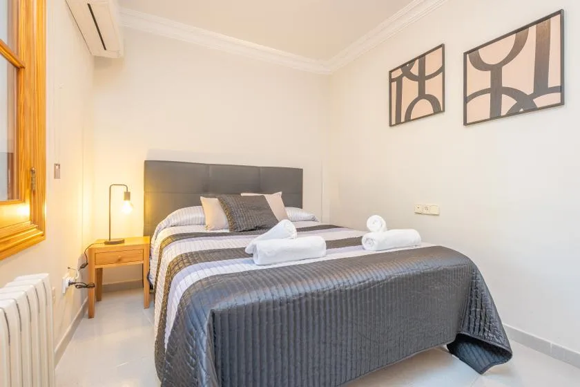 A bedroom with a neatly made bed and folded white towels.